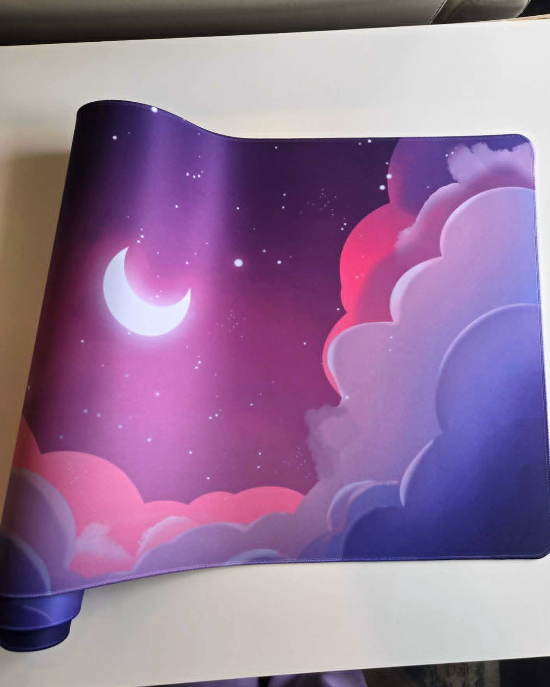 Mouse pad with a design of a night sky with clouds and a moon.